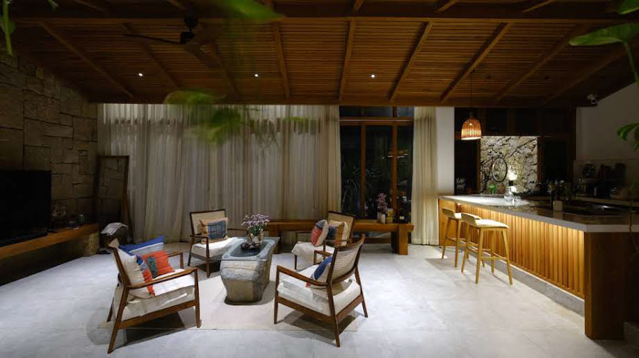 Không gian khách chính với một bức tường đá kết hợp trần gỗ giản dị